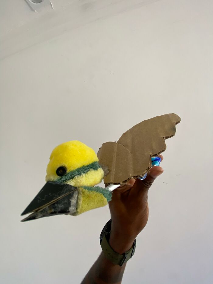 Hand holding a handmade mini bird mom crafted from cardboard and fabric resembling a great kiskadee bird. Hand holding a handmade mini bird mom crafted from cardboard and fabric resembling a great kiskadee bird.