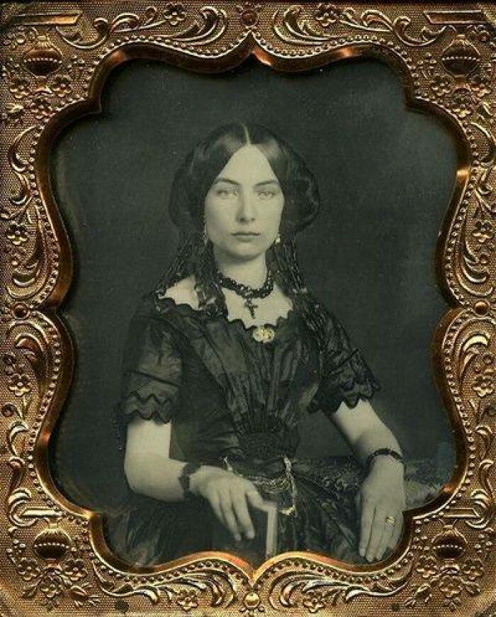 Victorian-Edwardian pictures of a woman in period dress with lace sleeves and layered jewelry in an ornate frame.