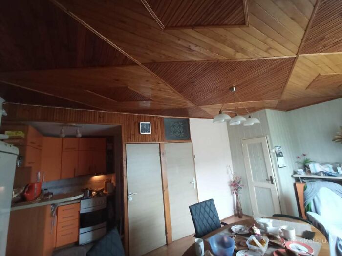 Interior view of a small kitchen and dining area with wooden ceiling in a wild real estate listing.