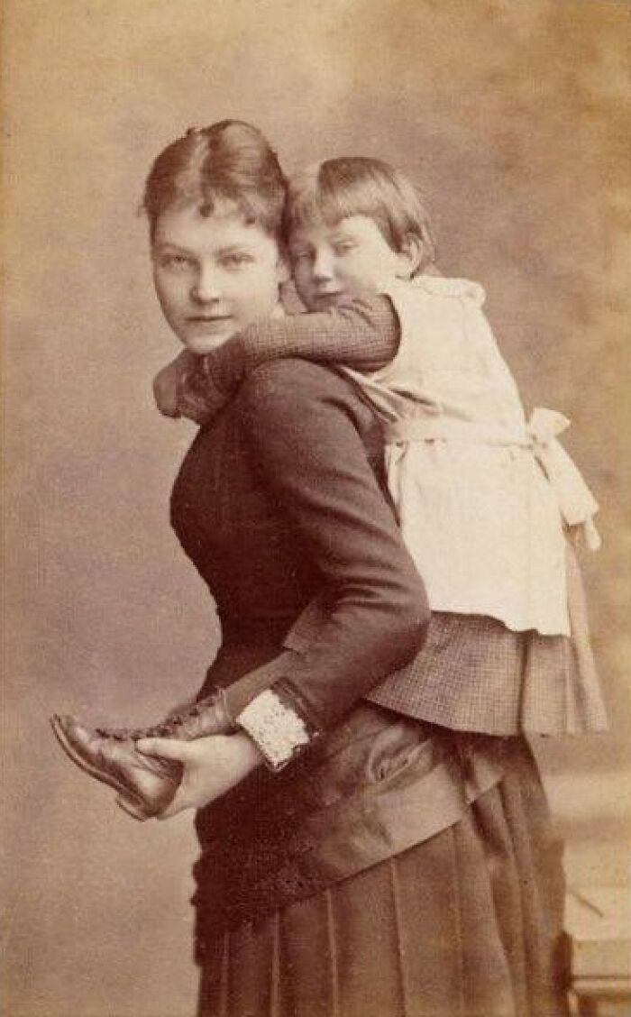 Victorian-Edwardian pictures showing a woman in period dress carrying a child on her back in a sepia tone portrait.