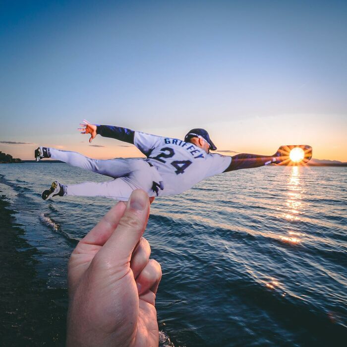 Hand holding a paper cutout of a baseball player diving to catch the sun over water, showing brilliant paper cutouts art. Hand holding a paper cutout of a baseball player diving to catch the sun over water, showing brilliant paper cutouts art.