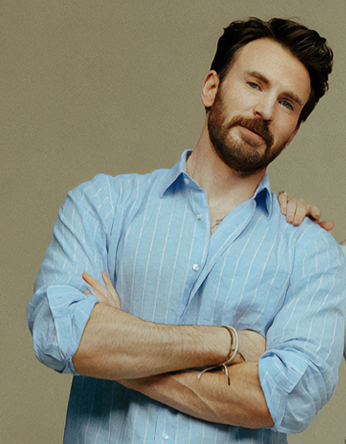 Chris Evans in a casual blue shirt with arms crossed, amid viral cheating rumors and scandalous blind items news.