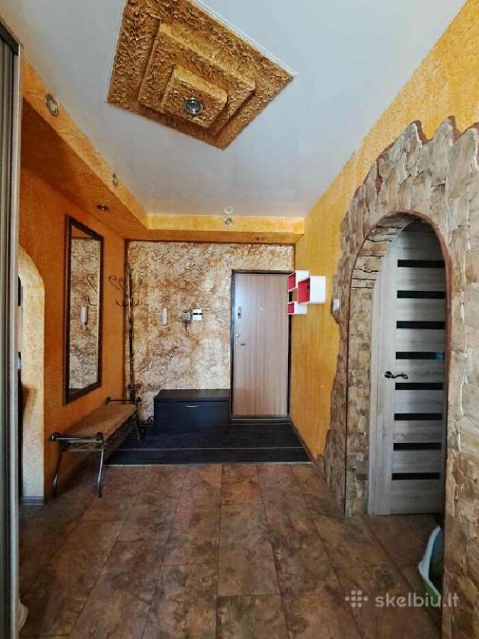 Entryway with textured walls, wooden door, stone arch, and unusual ceiling design in wild real estate listing interior.