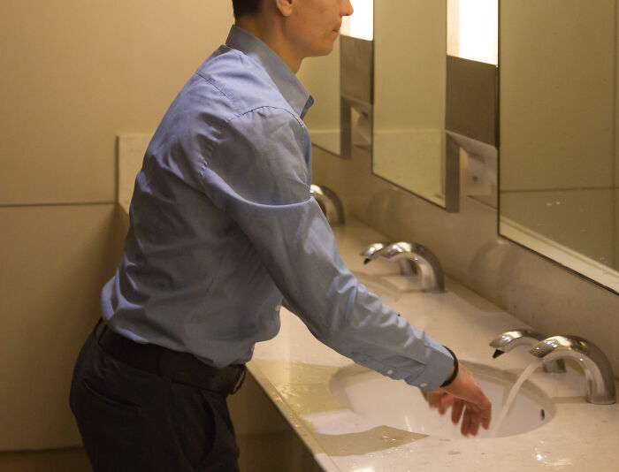 Man washing hands in public restroom sink, reflecting tension of real-life horror story moments faced by people.