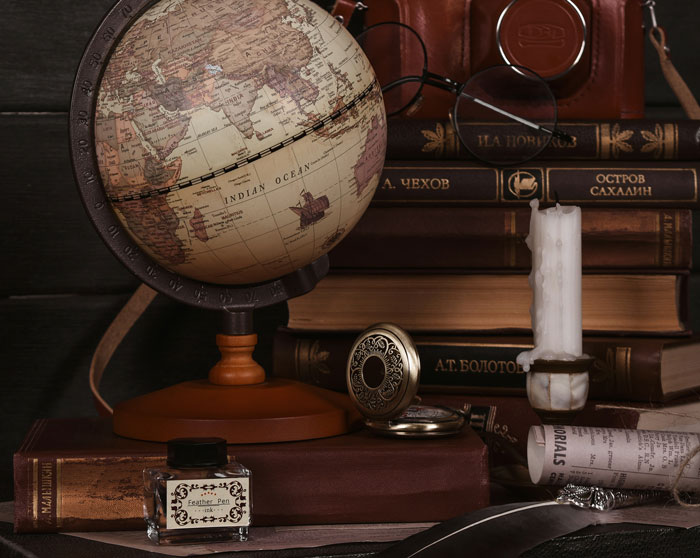 Vintage globe and old books arranged on a table, symbolizing family history and stories shared online about family drama.