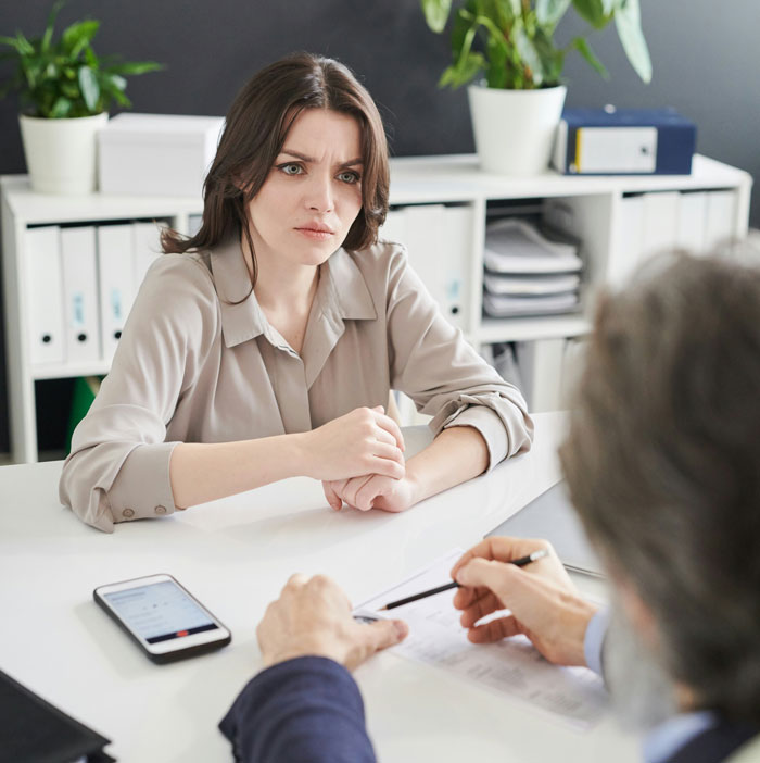 Woman showing a confused expression during a serious discussion, capturing a moment of instant karma in an office setting.
