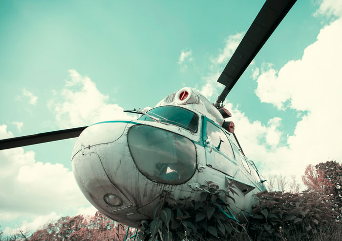 Abandoned helicopter surrounded by overgrown plants, capturing a creepy and terrifying moment for urban explorers.