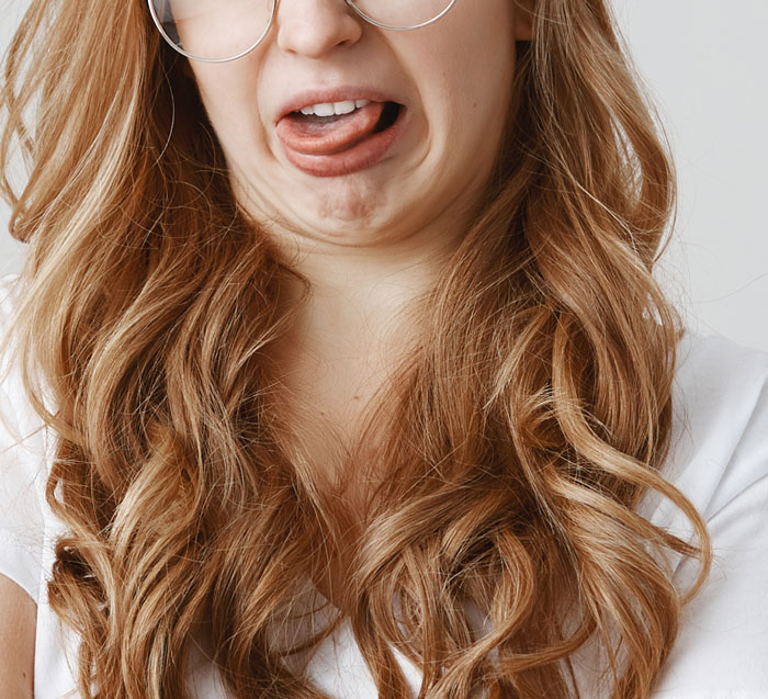 Young woman making a funny face with tongue out, capturing the humor in patients’ comments breaking serious hospital vibes.