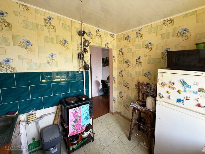 Small kitchen with floral wallpaper, old stove, and refrigerator, showcasing a wild real estate listing interior.