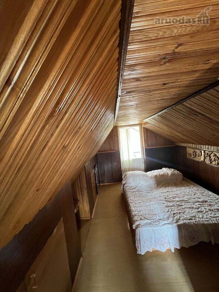 Cozy attic bedroom with slanted wooden walls and ceiling, featuring a double bed in unique real estate listing.