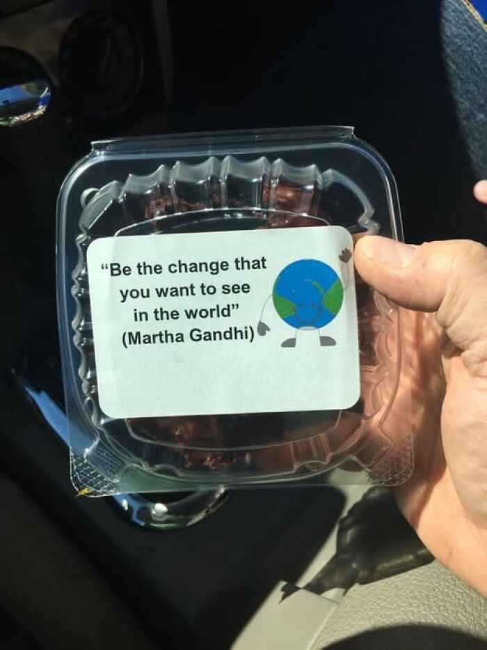 Hand holding a plastic container with a humorous autocorrect error quoting Martha Gandhi instead of Mahatma Gandhi.