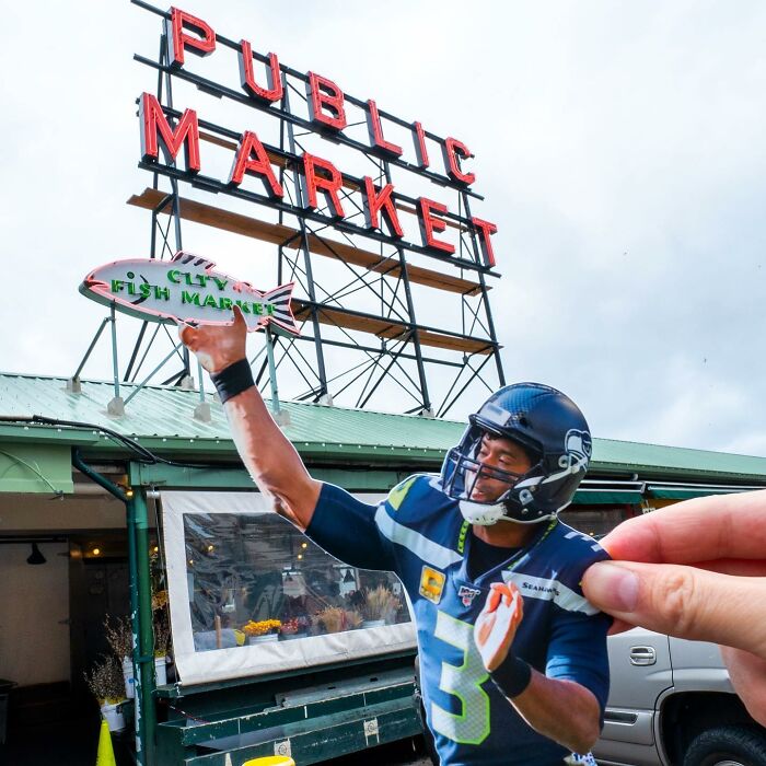 Hand holding paper cutout of football player interacting with Public Market sign in a street scene. Hand holding paper cutout of football player interacting with Public Market sign in a street scene.
