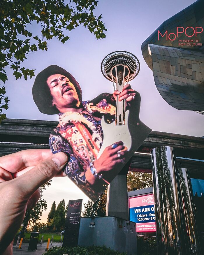 Hand holding a paper cutout of a guitarist with the Space Needle creatively used as the guitar neck in a brilliant paper cutout artwork. Hand holding a paper cutout of a guitarist with the Space Needle creatively used as the guitar neck in a brilliant paper cutout artwork.