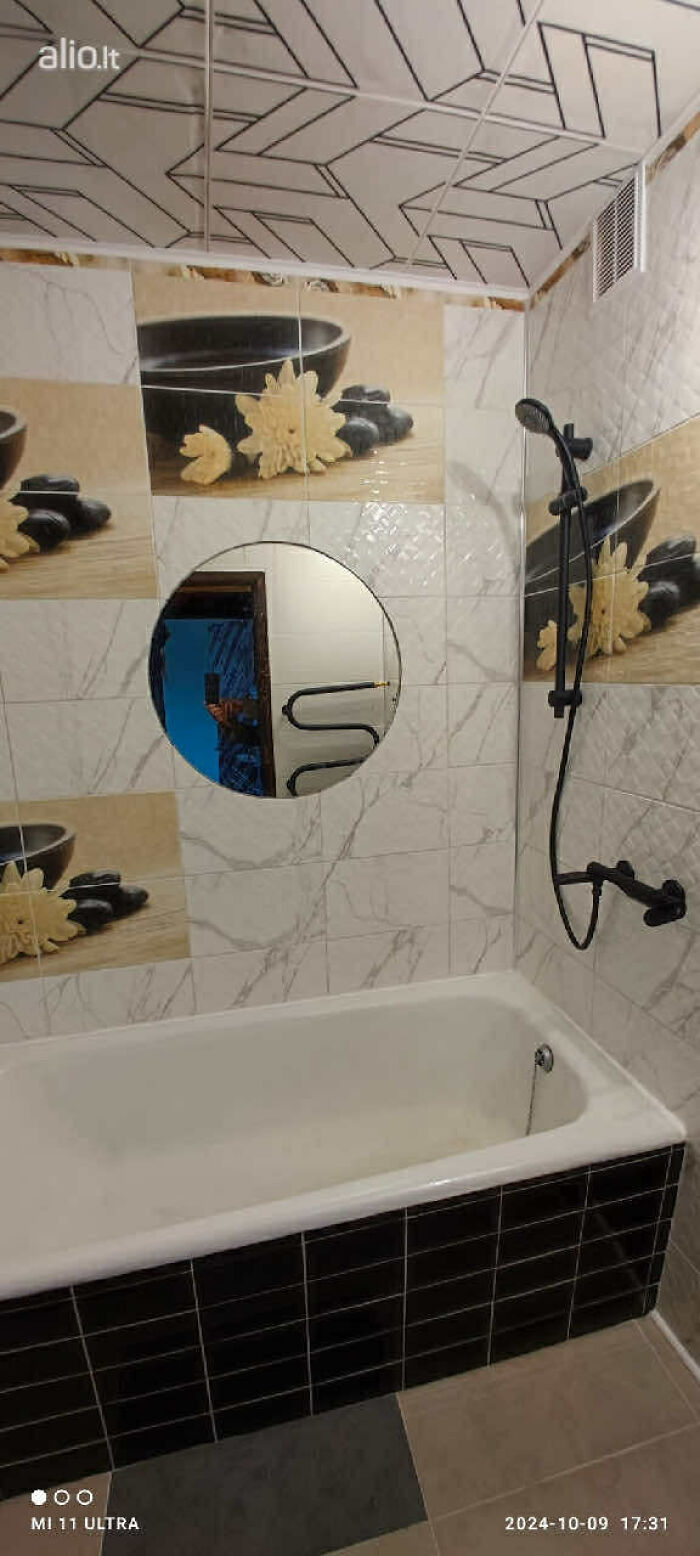 Bathroom with floral tile design, round mirror, and black shower fixtures in a wild real estate listing interior.