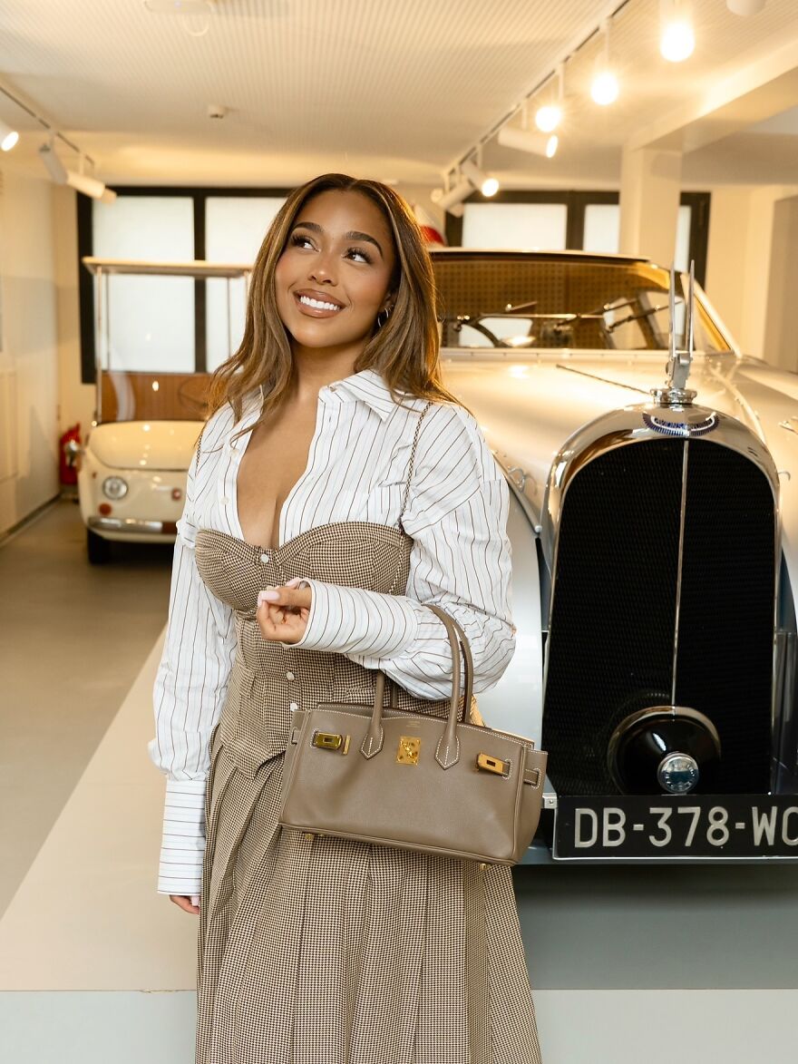 Jordyn Woods posing by vintage cars, representing celebrities on exclusive members-only fan pages and luxury lifestyle.