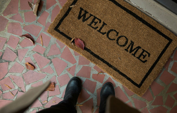Person standing on a tiled porch next to a welcome mat, illustrating frustration with HOA rules and regulations.
