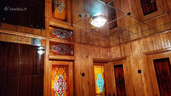 Wood-paneled room with stained glass windows and mirrored ceiling in wild real estate listing interior design.