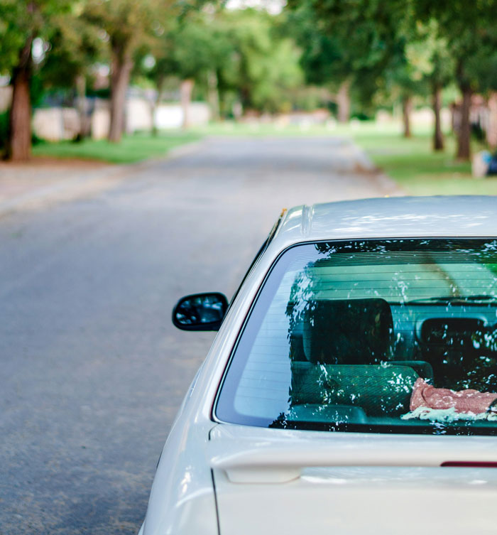 Silver car parked on a suburban street with trees, illustrating common HOA parking rules that frustrate residents