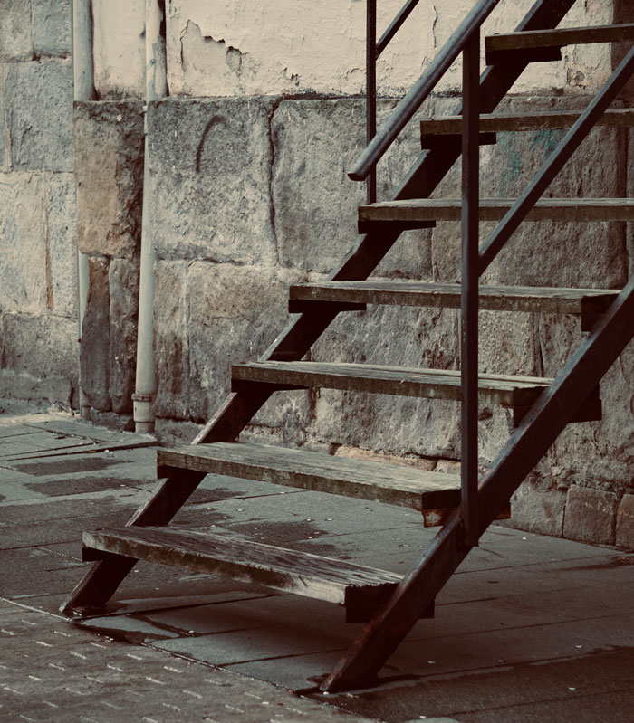 Rusty metal stairs against worn stone wall in an urban exploration site evoking creepy and terrifying moments.