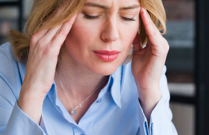 Woman stops treating her husband like a kid, feeling stressed and overwhelmed while holding her temples indoors.