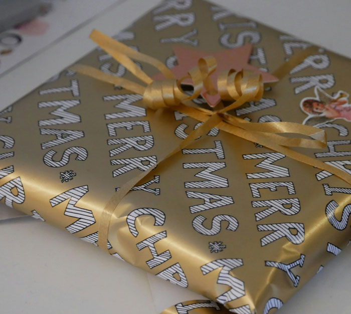 Gold-wrapped Christmas gift with curled ribbon, representing festive moments tied to family drama shared online.