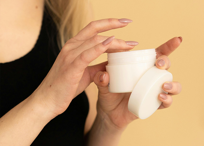 Person holding a white jar of cream with lid removed, illustrating horrible gifts people have actually received.