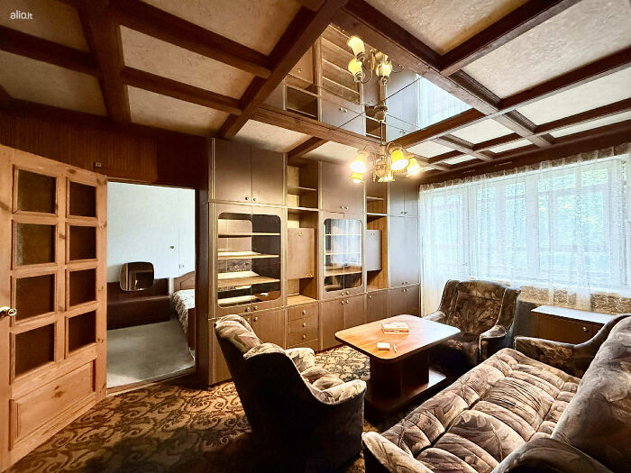 Vintage living room with wooden furniture and patterned carpet in a wild real estate listing interior design.