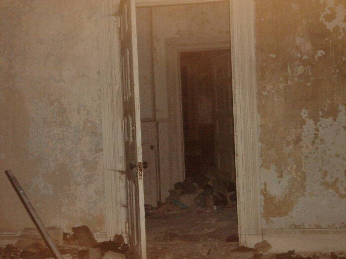 Abandoned, decaying hallway with peeling walls and debris, evoking creepy and terrifying moments for urban explorers.