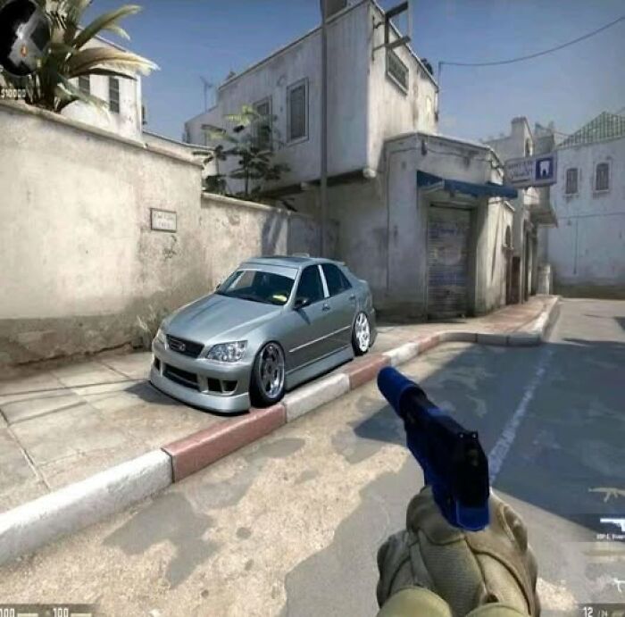 In-game view of a customized car on a city street and a player holding a pistol in a popular shooter game.