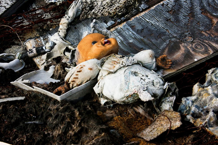 Creepy abandoned doll among decayed debris in a dark, eerie setting, evoking terrifying moments for urban explorers.
