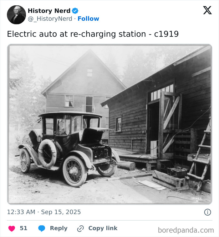 Black and white photo of an early electric car at a recharging station, showcasing rare and powerful history moments.