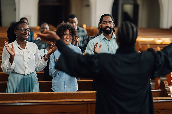 Congregation raising hands in church worship led by pastor, reflecting the theme of prayer and church attendance conflict.