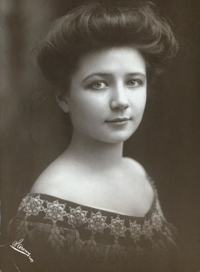 Victorian-Edwardian picture of a young woman with styled hair and lace dress, captured in soft sepia tones.