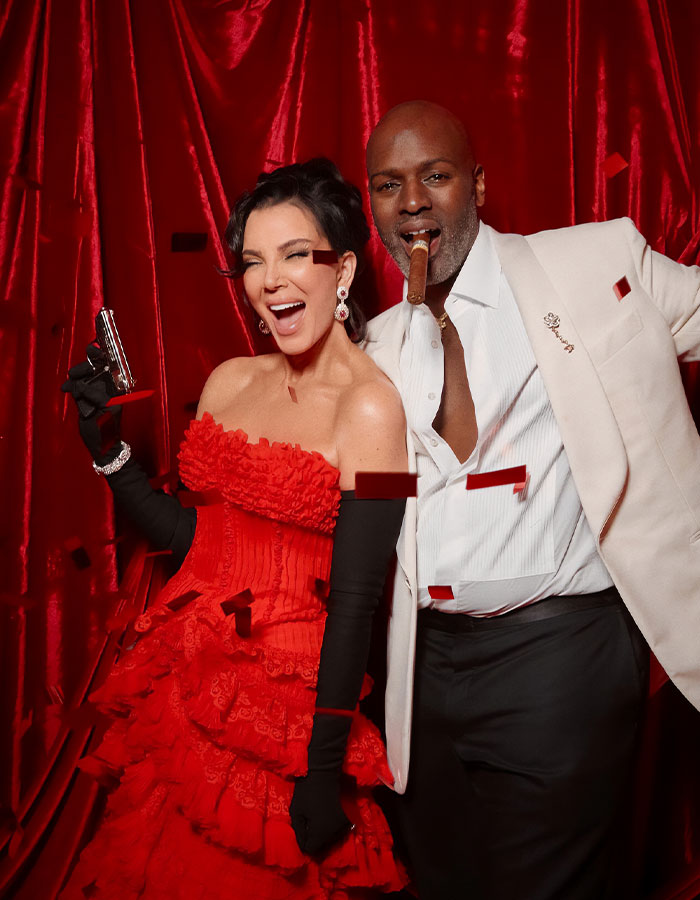 Guests at Kris Jenner's 70th birthday bash pose in elegant attire amid red confetti and dramatic red backdrop. Guests at Kris Jenner's 70th birthday bash pose in elegant attire amid red confetti and dramatic red backdrop.