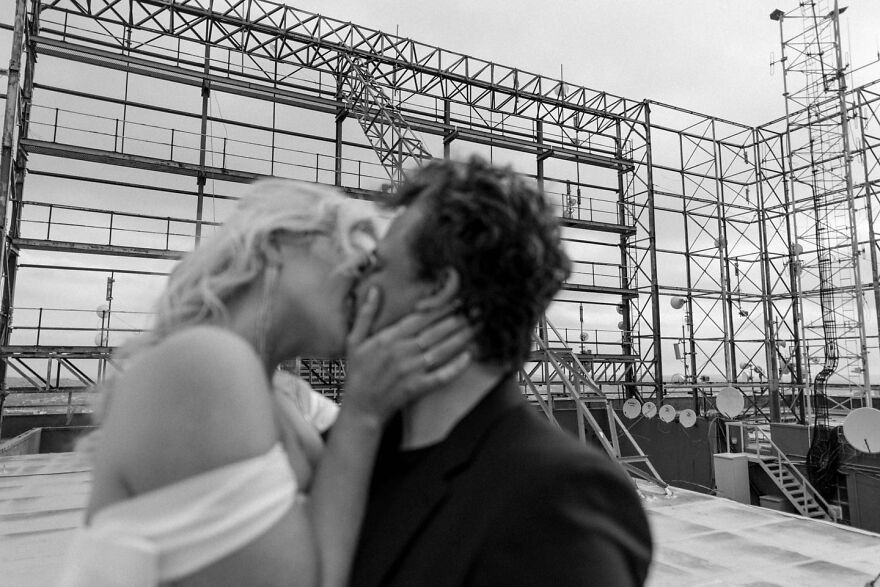Couple sharing a romantic kiss on an industrial rooftop, illustrating types of kisses and their cultural meaning.