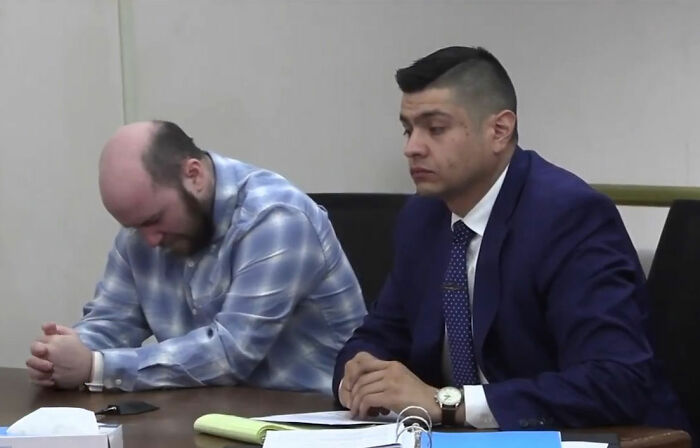 Man in plaid shirt and lawyer in suit at table during legal proceeding about man leaving daughter in burning car.