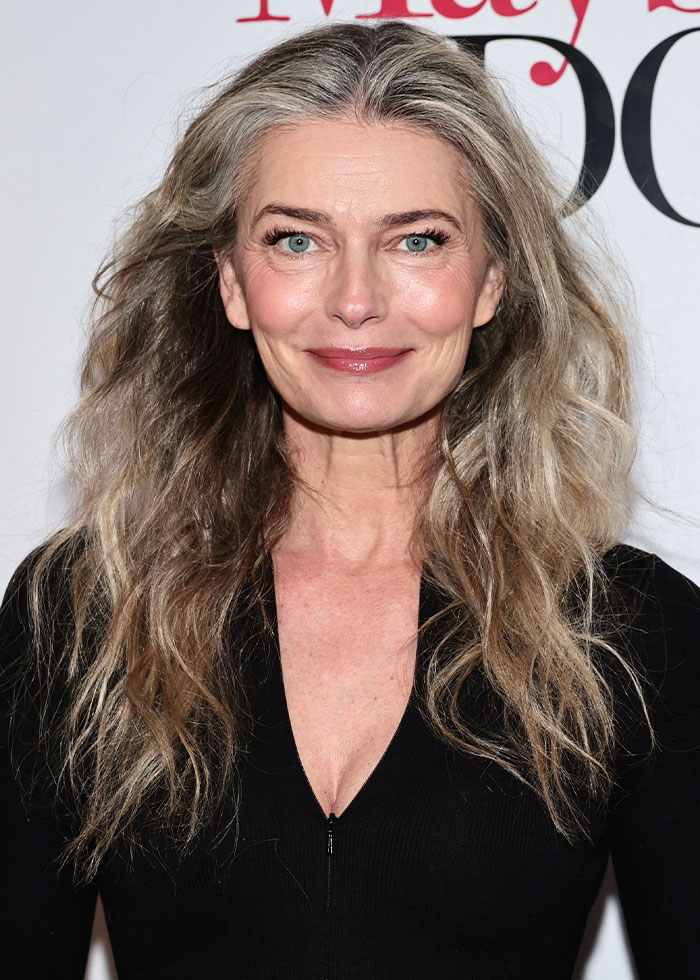 Paulina Porizkova, 60, smiling with long wavy hair, wearing a black top, embracing her perfect imperfections.