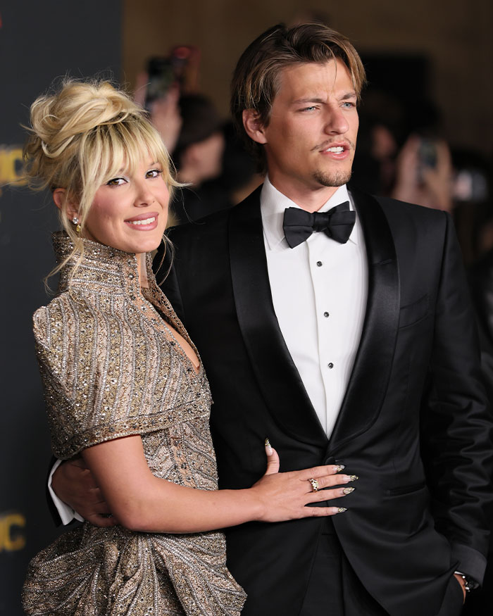 A couple dressed elegantly at a formal event, highlighting fans' reactions on Millie Bobby Brown legally changing her name. A couple dressed elegantly at a formal event, highlighting fans' reactions on Millie Bobby Brown legally changing her name.