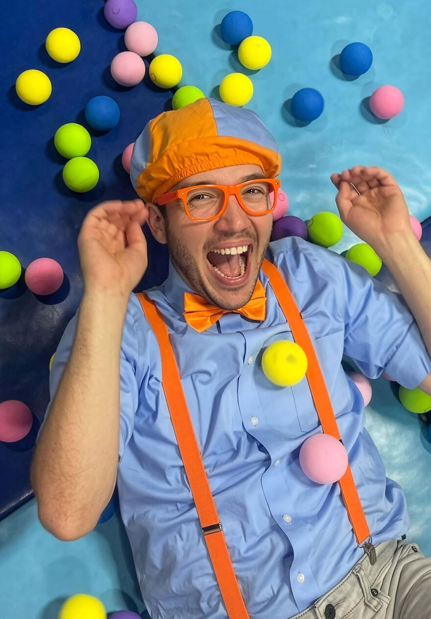 A Blippi wearing orange suspenders and bow tie, colorful hat and glasses, smiling among yellow, pink, blue, and green balls related to Blippis. A Blippi wearing orange suspenders and bow tie, colorful hat and glasses, smiling among yellow, pink, blue, and green balls related to Blippis.