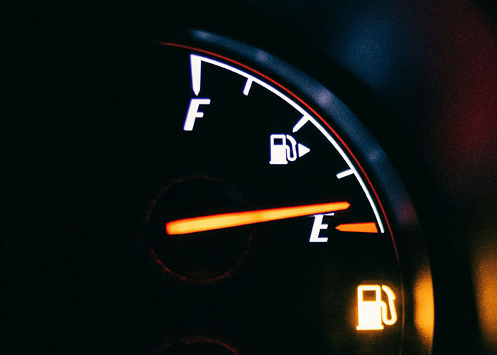 Car fuel gauge needle near empty with illuminated low fuel warning light in a dark dashboard, highlighting common knowledge insights.