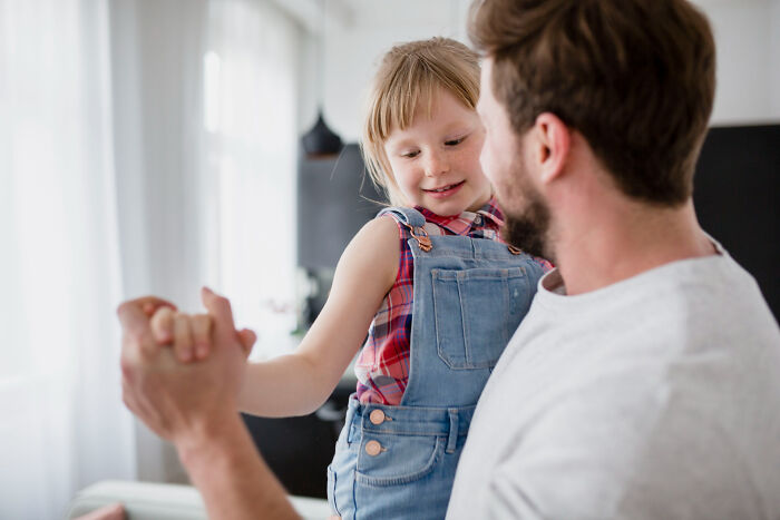 Man holding and playing with a young girl indoors, highlighting parenting challenges with kids every weekend. Man holding and playing with a young girl indoors, highlighting parenting challenges with kids every weekend.