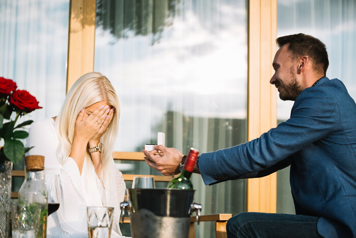 Man proposing with a ring to a surprised woman, capturing a moment of lessons learned and never again regrets.