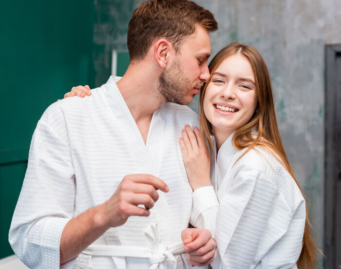 Couple in white robes sharing a tender moment, illustrating surprising habits discovered about their partner after moving in.