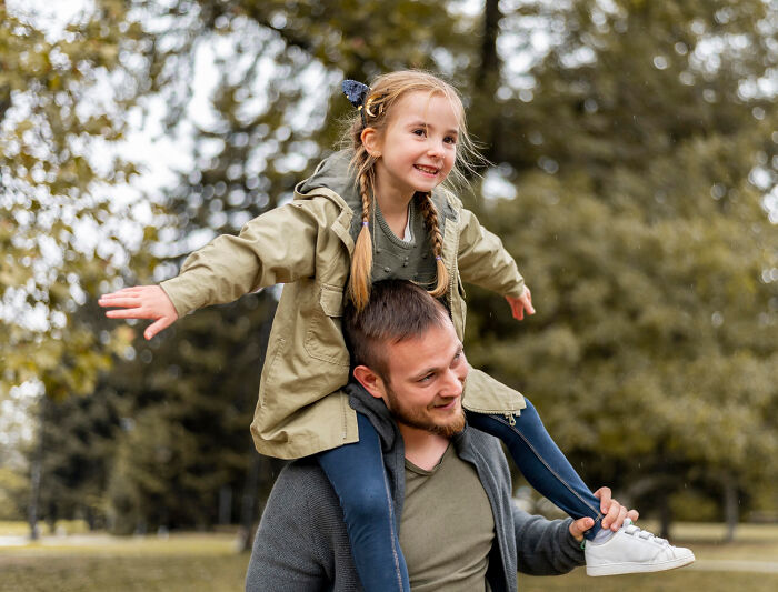 Father giving his daughter a piggyback ride outdoors, capturing joyful moments of realizing compulsory things are optional.