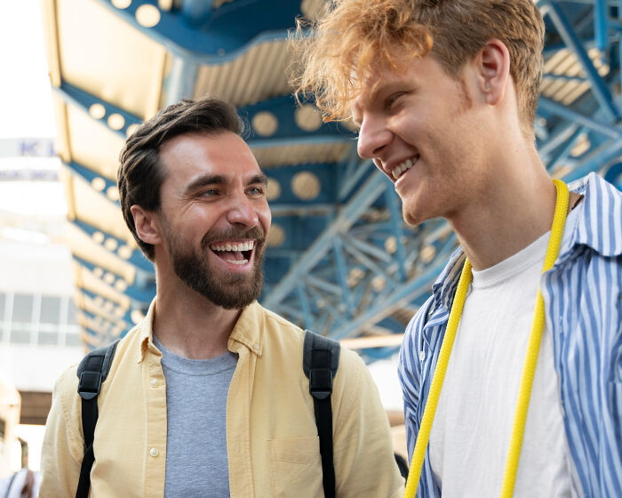 Two young men smiling and talking outdoors, reflecting signs a child never loved properly through positive connection.