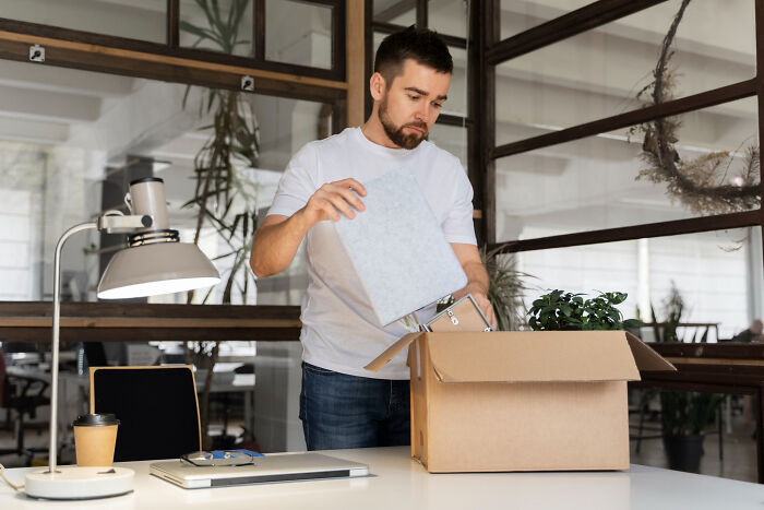 Man packing belongings into a box in an office, symbolizing people who disappeared to start new lives and experiences.