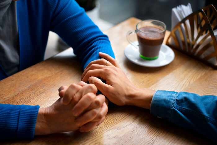 Two people holding hands on a wooden table, symbolizing learning lessons and never messing up again. Two people holding hands on a wooden table, symbolizing learning lessons and never messing up again.