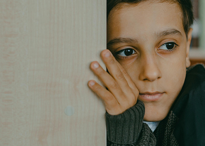 Boy leaning on wooden surface looking sad and thoughtful, illustrating horrible gifts people have actually received.