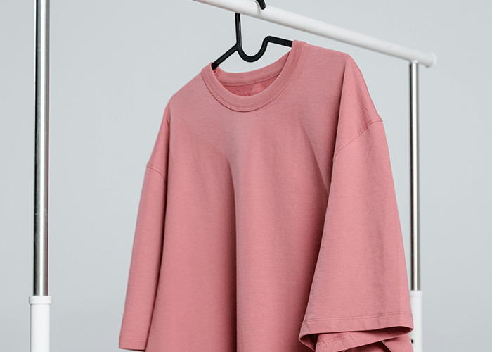 Pink oversized t-shirt on hanger, representing horrible gifts people have actually received in a personal clothing item.