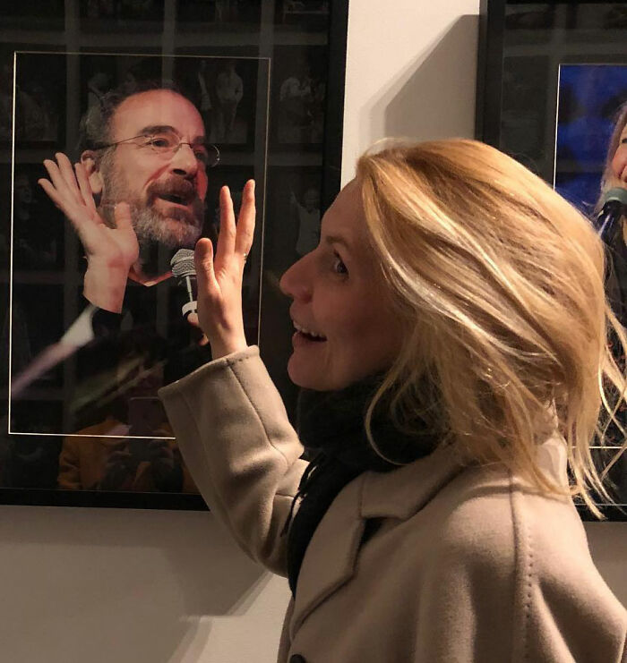 Claire Danes smiling and touching a glass frame, showcasing her quivering chin in a candid moment indoors. Claire Danes smiling and touching a glass frame, showcasing her quivering chin in a candid moment indoors.